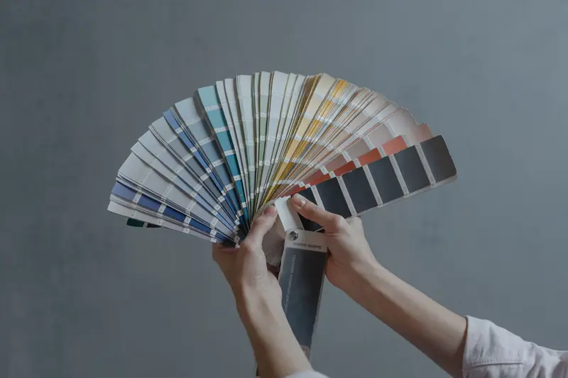 Hand holding a fan deck of paint colour swatches